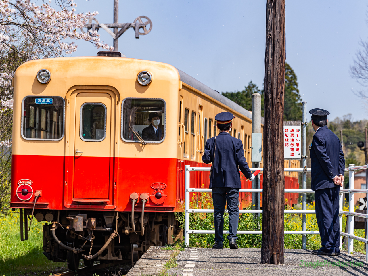 列車を見送る駅員さん２名とそれを見守る車掌さん